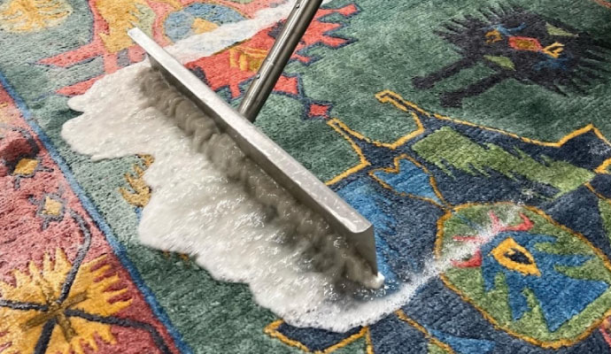 Professional cleaning a rug using soapy water